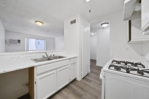 A kitchen with a white counter top and a white stove top oven.