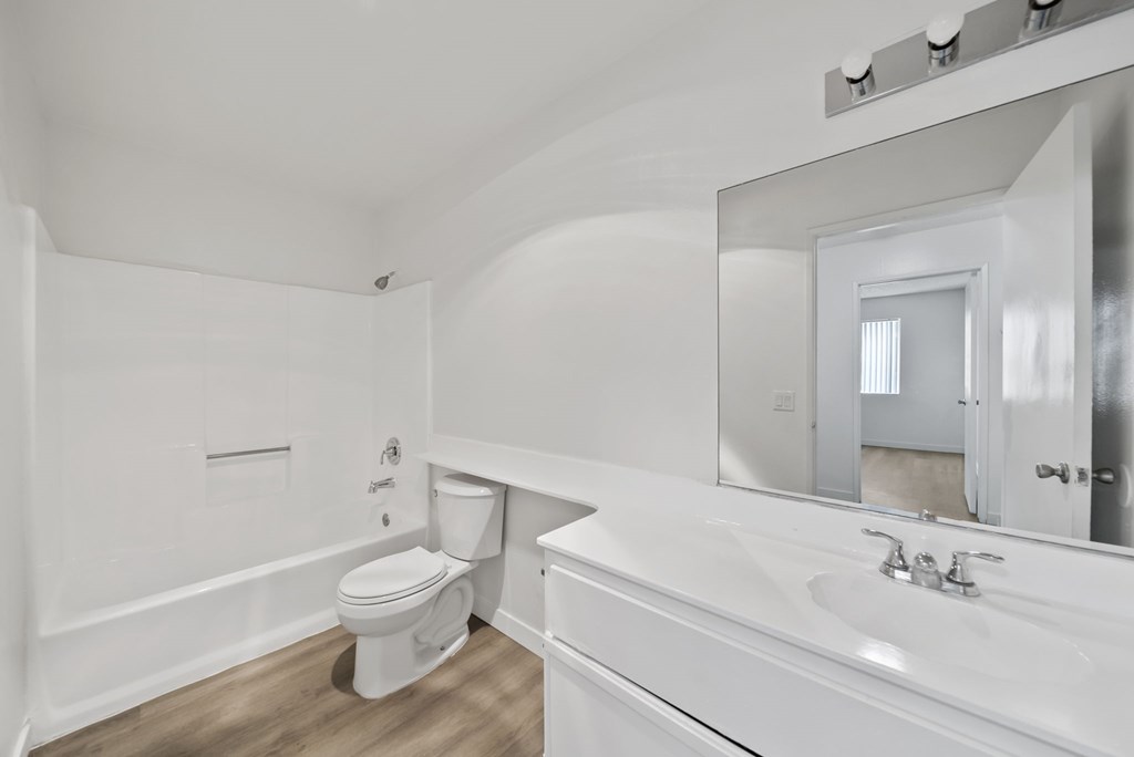 A white bathroom with a toilet, sink, and mirror.