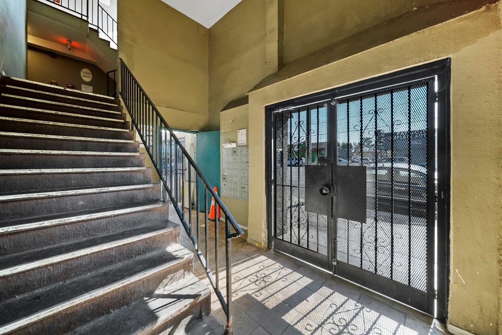 A staircase with a metal railing leads to a black gate.