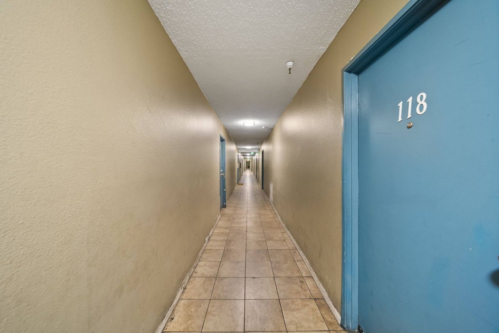 A long hallway with a blue door on the right.
