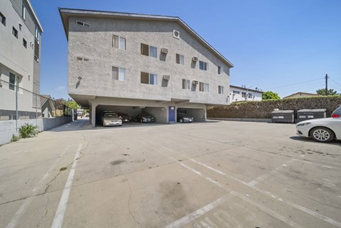 A parking lot in front of a concrete building with a car parked in it.