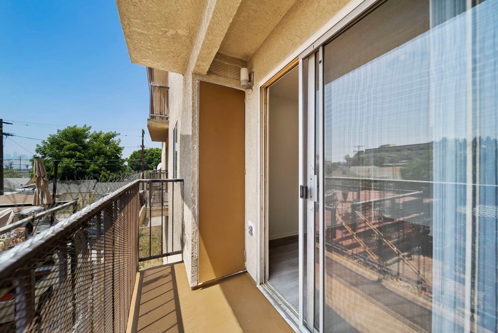 A balcony with a glass door leading to a building.