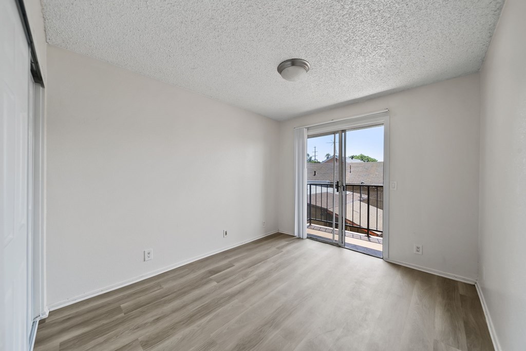 A room with a sliding glass door leading to a balcony.