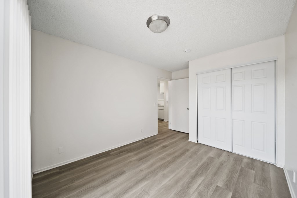A room with a white door and wooden flooring.