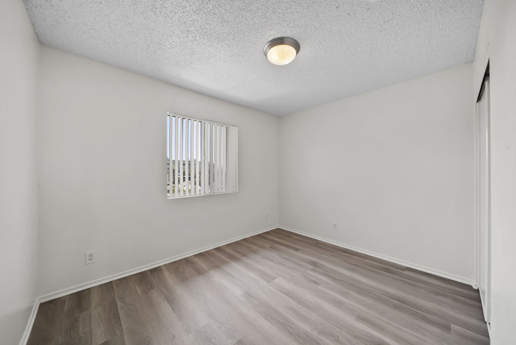 A room with a window and wooden flooring.