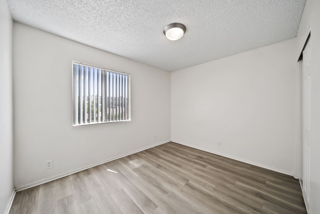 A room with a window and wooden flooring.