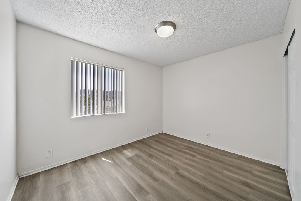 A room with a window and wooden flooring.