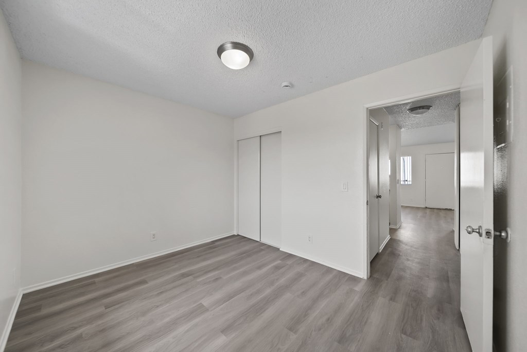 A spacious room with wood flooring and white walls.