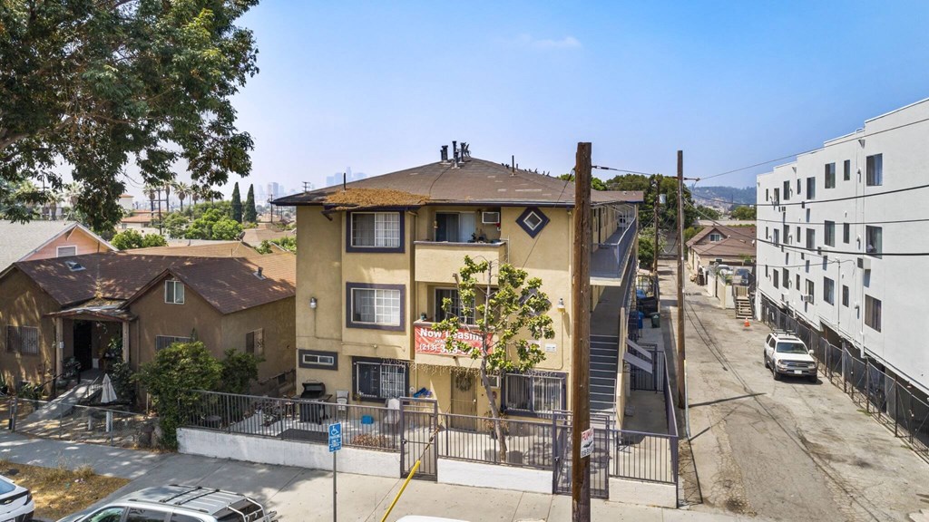 A street view of a residential area with a yellow building in the foreground.
