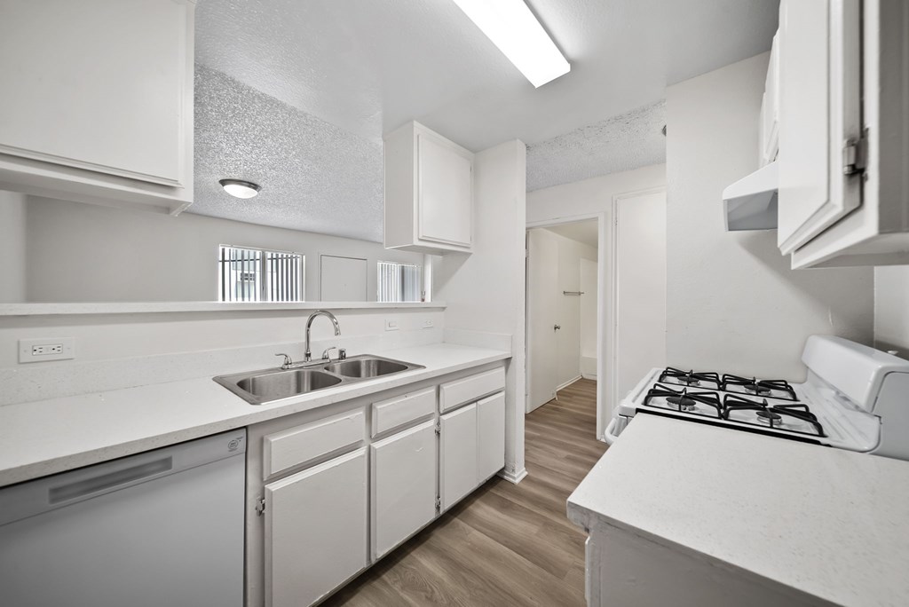 A white kitchen with a stove top oven and sink.