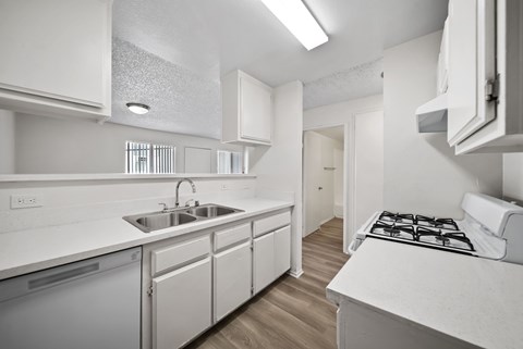 A white kitchen with a stove top oven and sink.