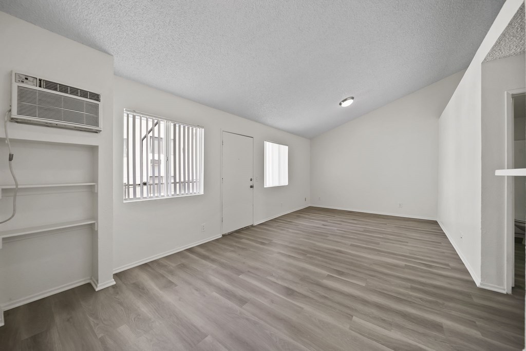 A room with wooden flooring and a window with blinds.