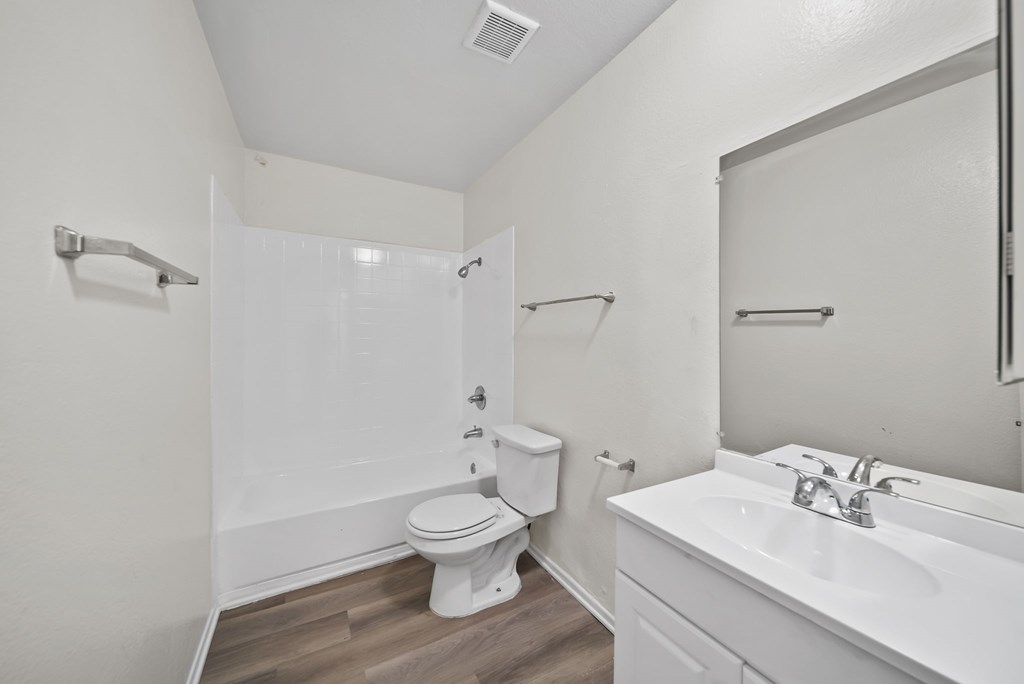 A white bathroom with a toilet, sink, and shower.