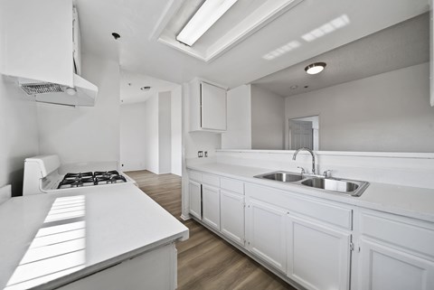 A white kitchen with a stove top oven and a sink.