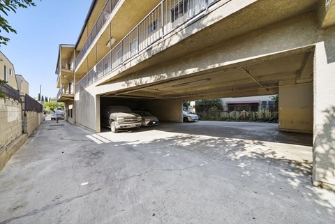 A car is parked in a garage under a concrete building.