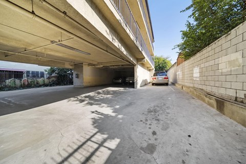 A concrete parking area under a bridge with a car parked in the distance.