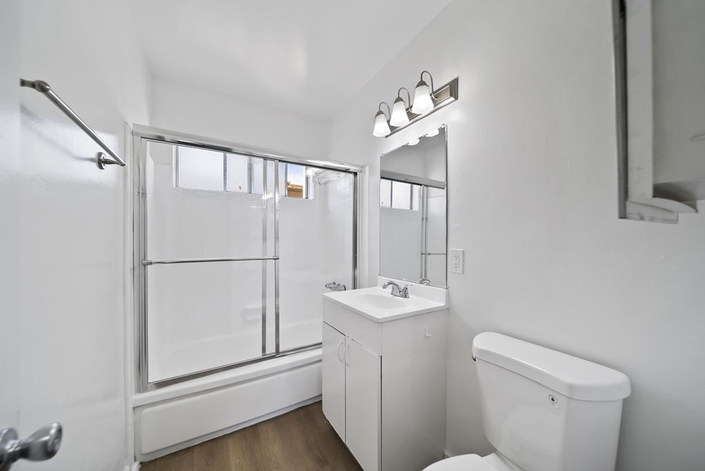 A white bathroom with a toilet, sink, and mirror.