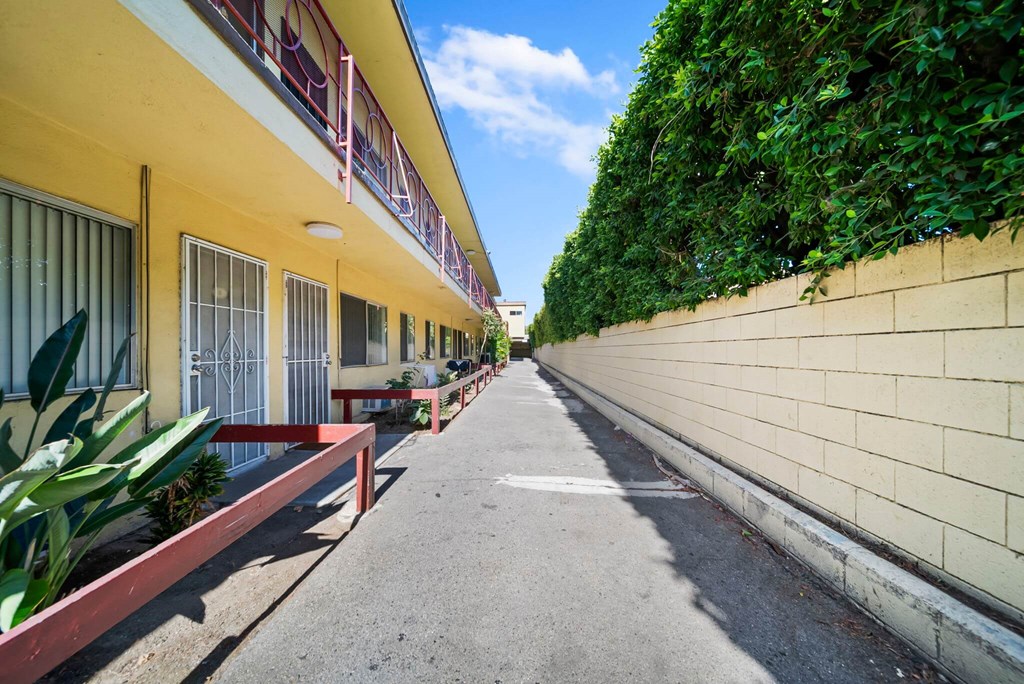 A yellow building with a red railing and a green plant on the side.