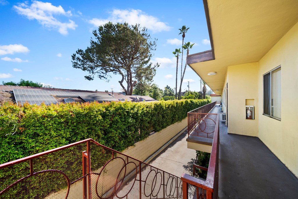A balcony with a railing and a tree in the background.