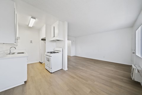 A kitchen with white cabinets and a wooden floor.