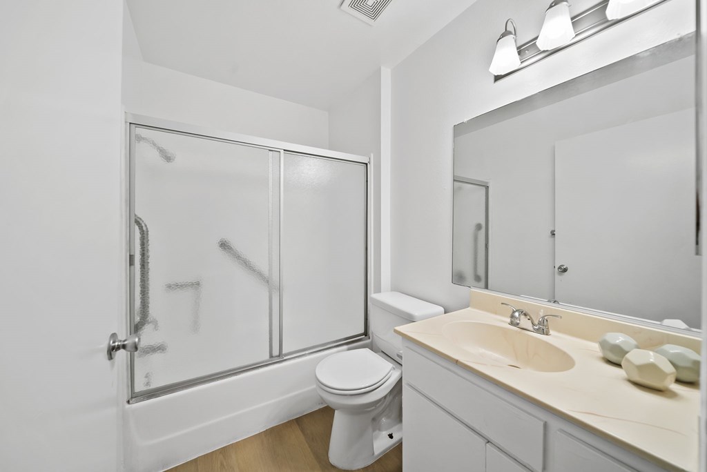 A white bathroom with a toilet, sink, and shower.