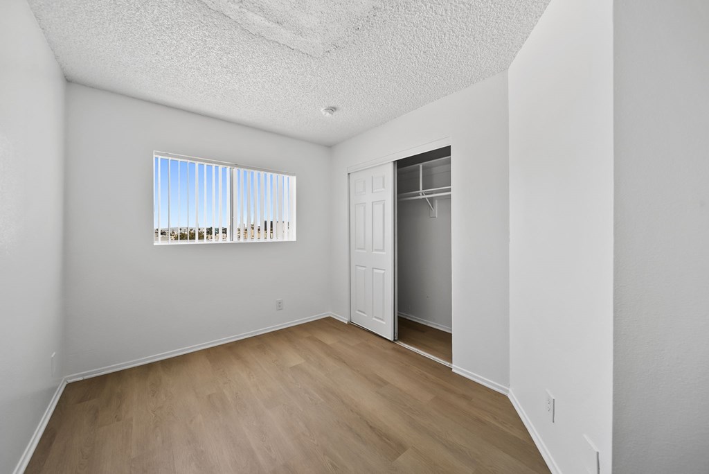 A room with a wooden floor and a window with blinds.