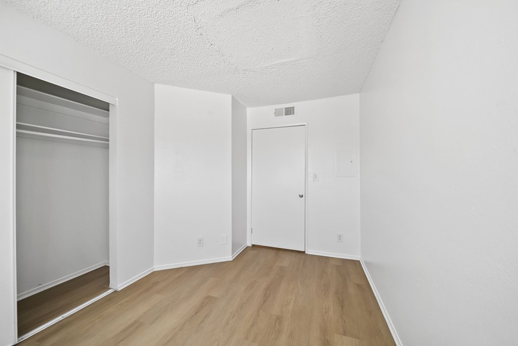 A white room with a door and a fridge.