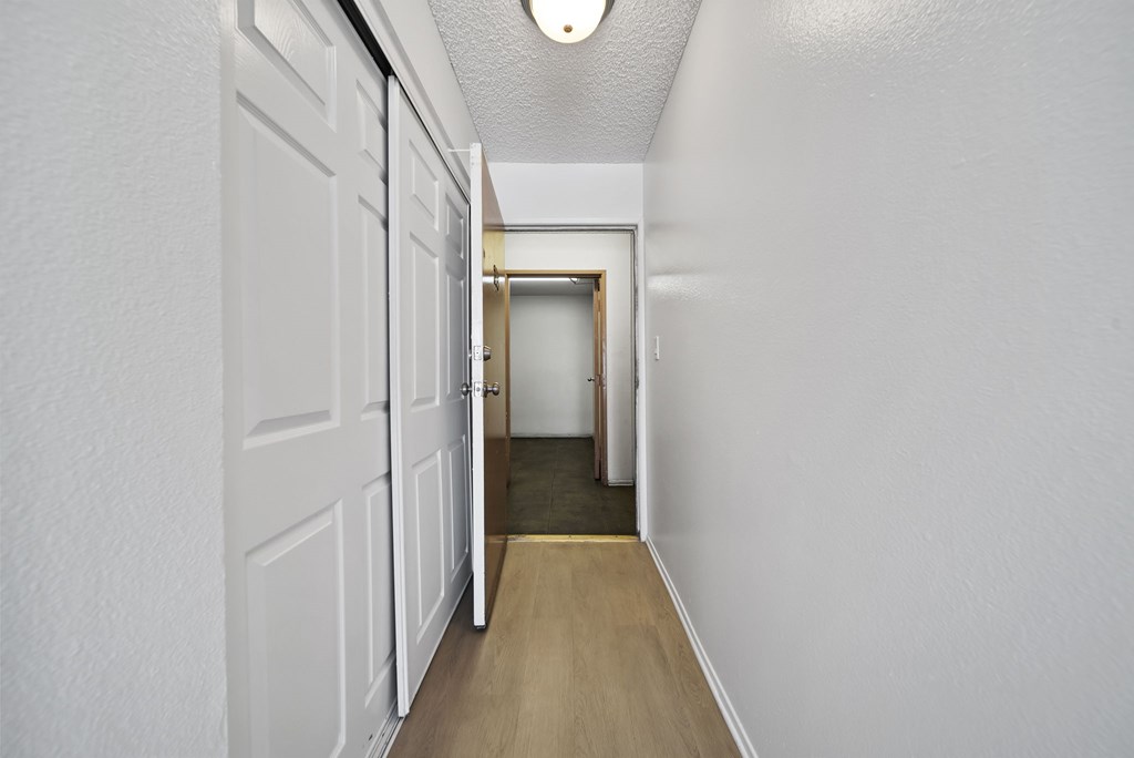 A long hallway with white walls and wood flooring.