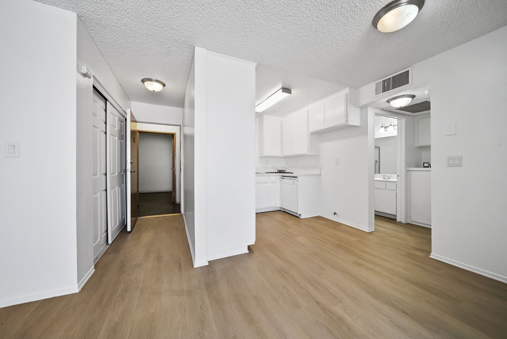A kitchen with white cabinets and a wooden floor.