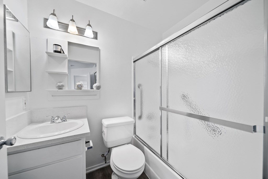 A white bathroom with a toilet, sink, and mirror.