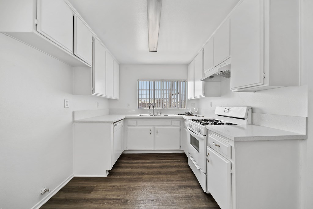 A white kitchen with wooden floors and white appliances.