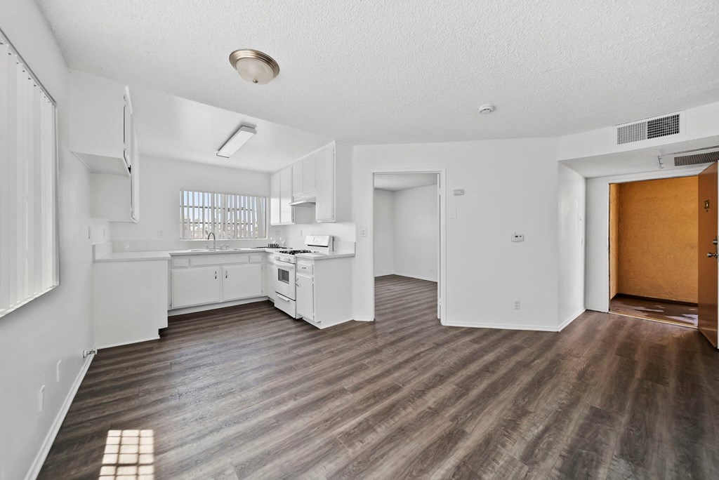 A kitchen with white cabinets and a wooden floor.