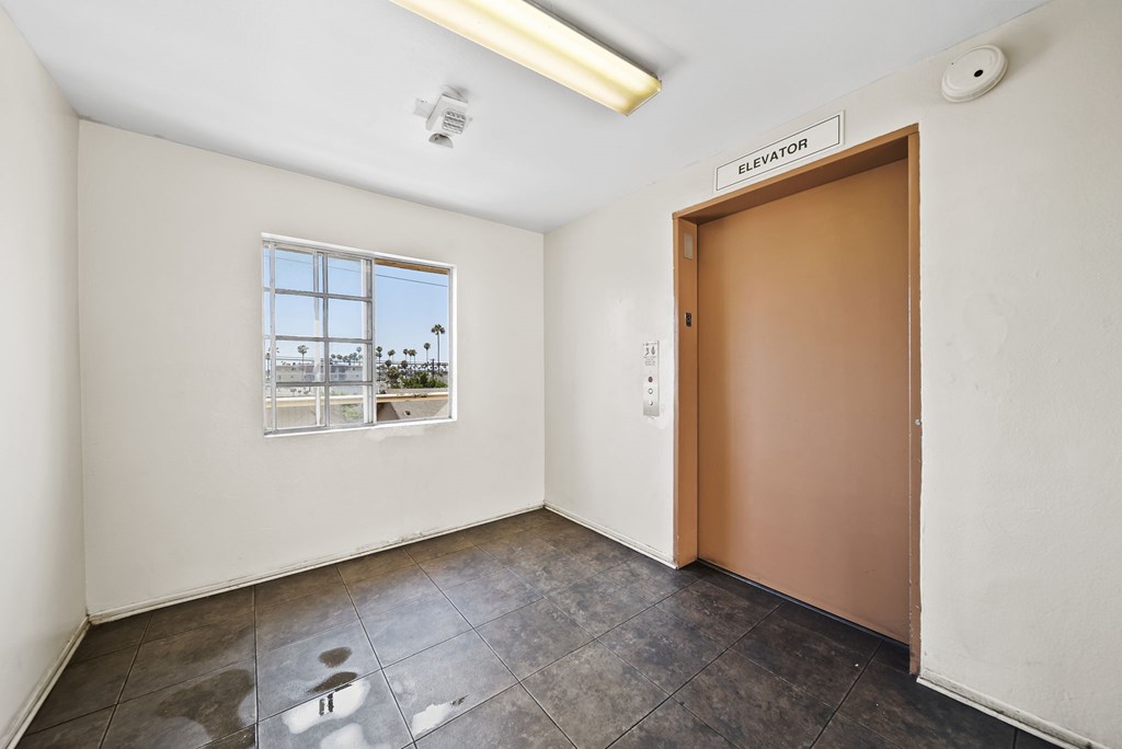 A room with a brown door and a window showing a cityscape.