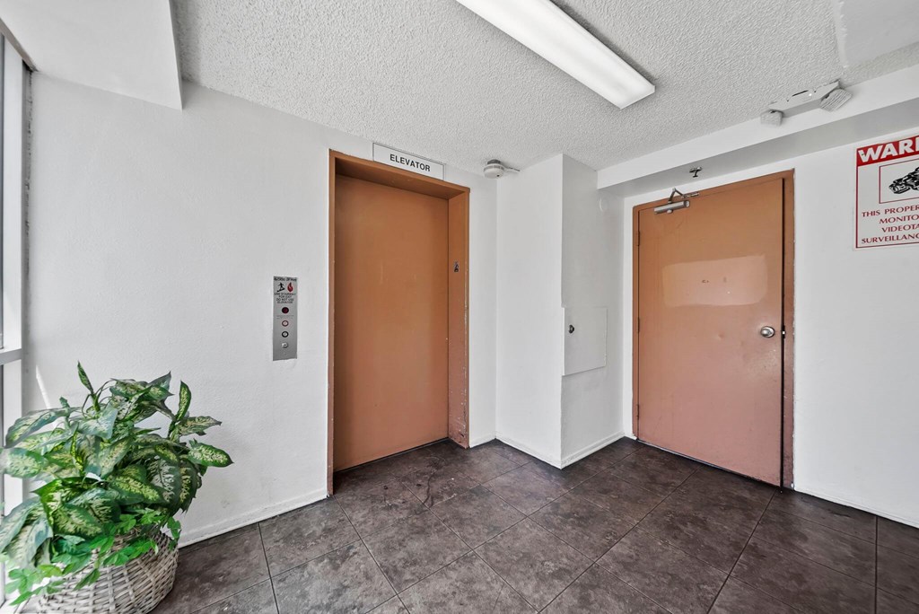 A room with two elevator doors and a sign on the wall.