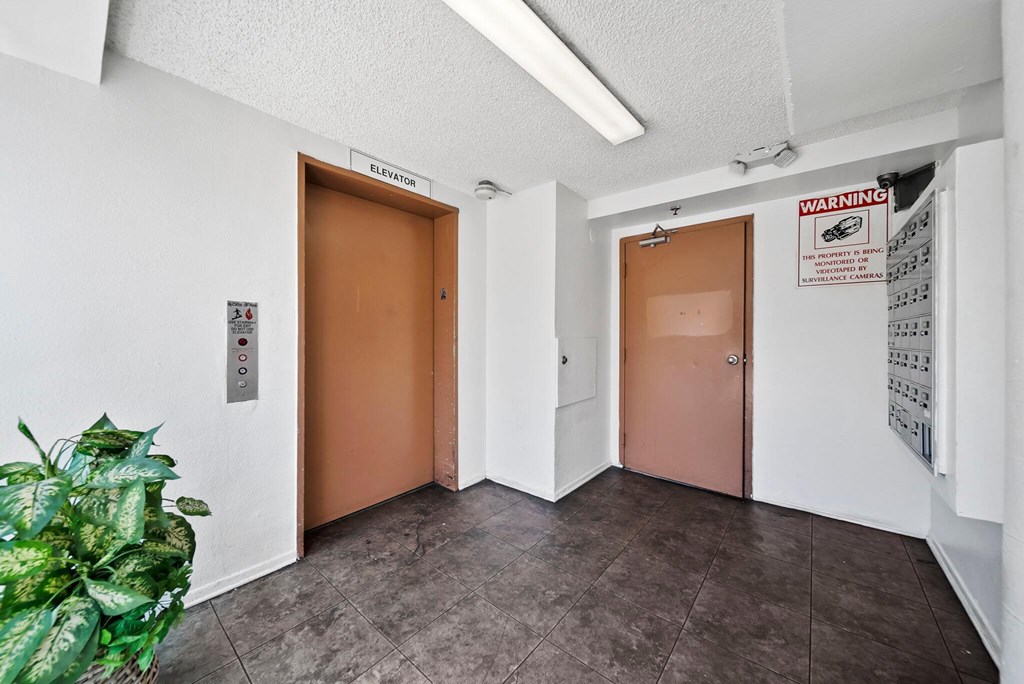 A hallway with two doors and a sign on the wall.