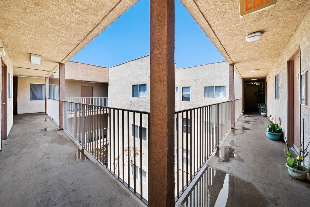 A balcony with a metal railing and potted plants.