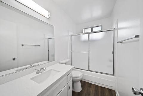 A white bathroom with a toilet, sink, and shower.