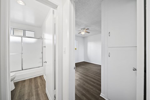 A white hallway with wood flooring and a ceiling fan.