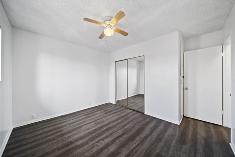A room with a ceiling fan and wooden flooring.