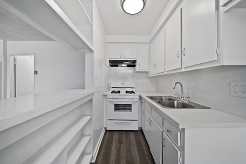 A modern kitchen with white cabinets and a wooden floor.