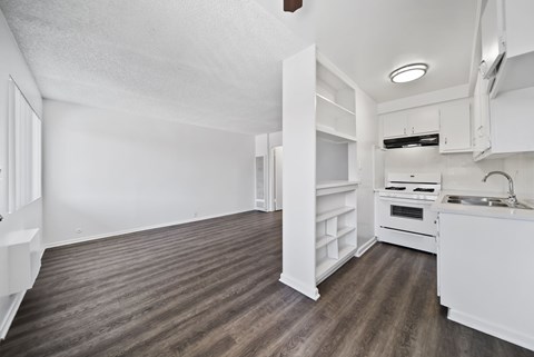 A kitchen area with a sink, stove, and cabinets.