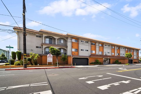 A street view of a building with a red and white sign in front of it.