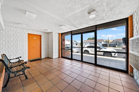 A room with a tiled floor and a view of a parking lot through the windows.