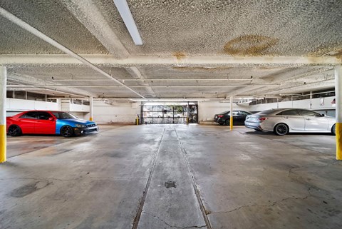 A parking garage with a red car on the left and a white car on the right.