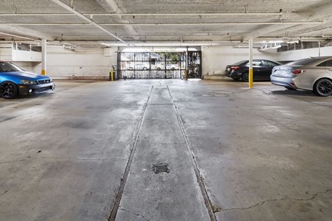A parking garage with a blue car on the left and a silver car on the right.