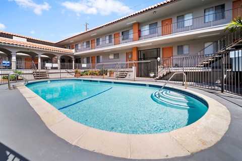 A swimming pool in front of a building with orange and white walls.