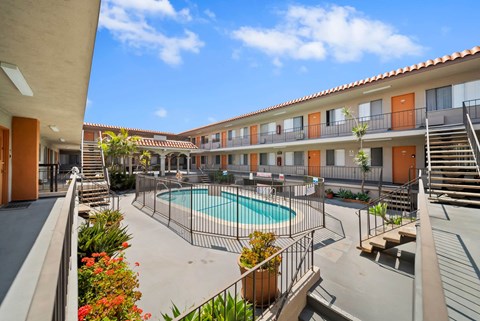 A pool surrounded by a fence and a building with orange doors.