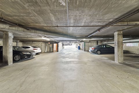 A parking garage with cars parked on both sides of the aisle.