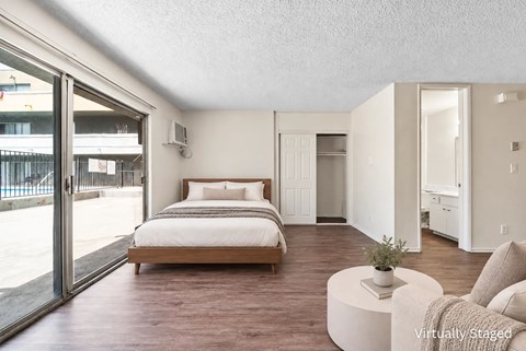 A bedroom with a bed, a couch, and a plant.