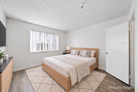 A bedroom with a bed, nightstand, and window.